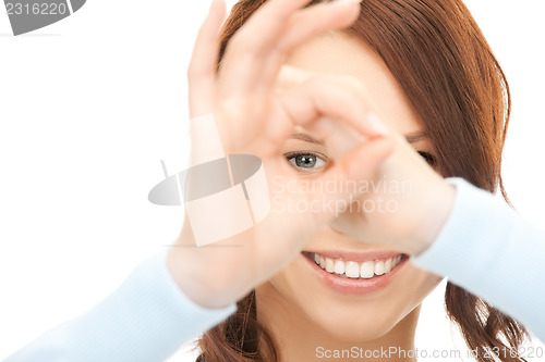 Image of lovely woman looking through hole from fingers