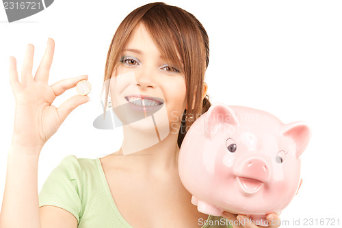Image of lovely teenage girl with piggy bank and coin