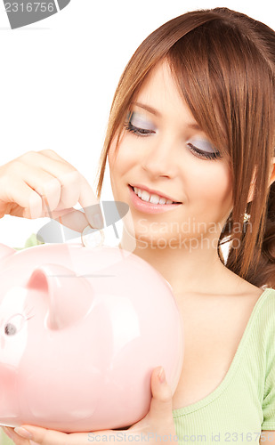 Image of lovely teenage girl with piggy bank and coin