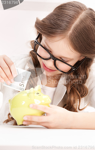 Image of little girl with piggy bank and money