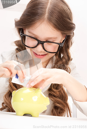 Image of little girl with piggy bank and money