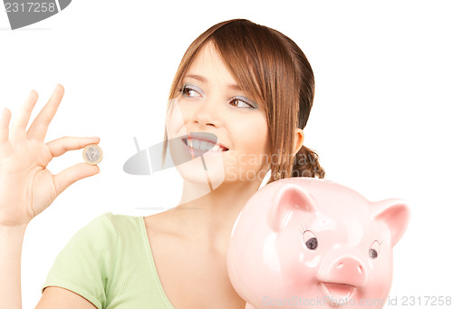 Image of lovely teenage girl with piggy bank and coin