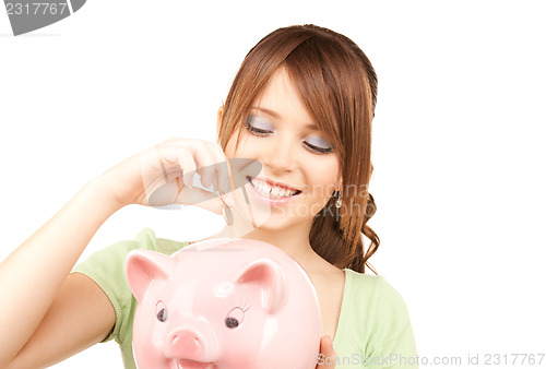 Image of lovely teenage girl with piggy bank and coin
