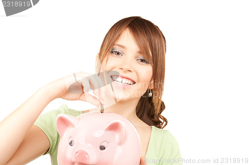 Image of lovely teenage girl with piggy bank and coin