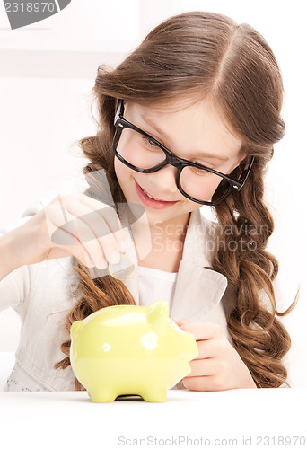 Image of little girl with piggy bank and coin