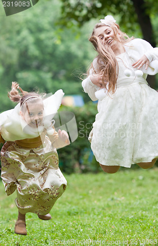 Image of Two little beautiful girls jumping in a park