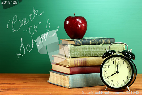 Image of School Books, Apple and Clock on Desk at School