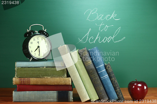 Image of School Books, Apple and Clock on Desk at School