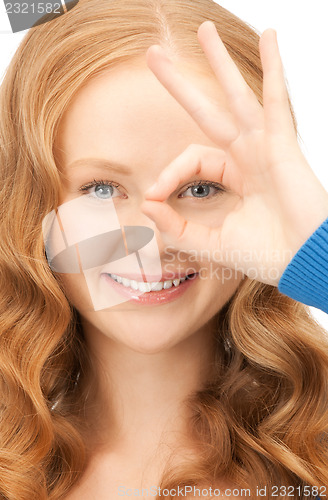 Image of lovely woman looking through hole from fingers