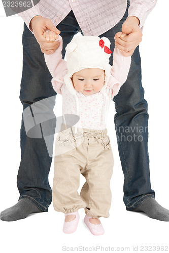 Image of baby making first steps with father help