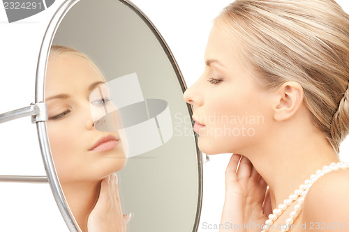 Image of beautiful woman with pearl beads and mirror