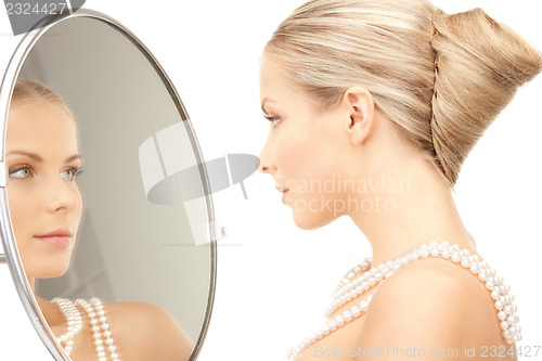 Image of beautiful woman with pearl beads and mirror