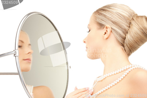 Image of beautiful woman with pearl beads and mirror