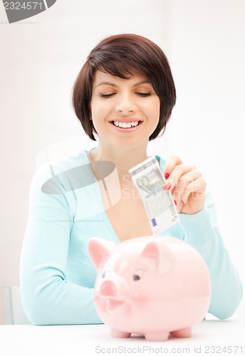 Image of lovely woman with piggy bank and money