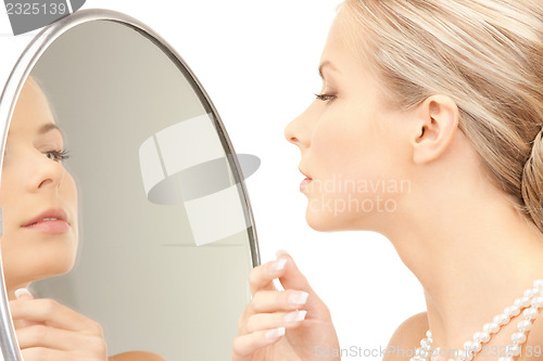 Image of beautiful woman with pearl beads and mirror