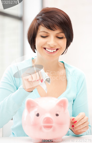 Image of lovely woman with piggy bank and money