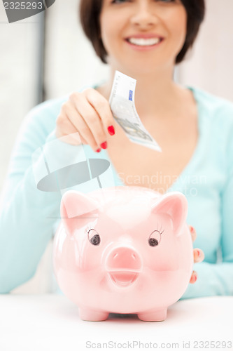 Image of lovely woman with piggy bank and money