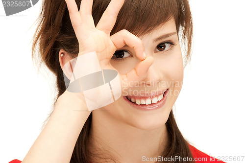 Image of teenage girl looking through hole from fingers