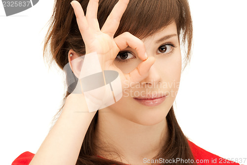 Image of teenage girl looking through hole from fingers