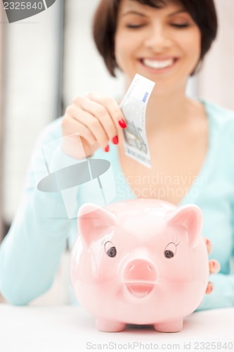 Image of lovely woman with piggy bank and money