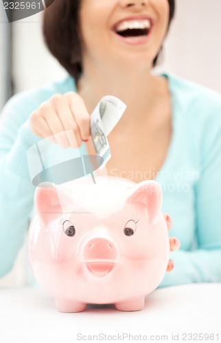 Image of lovely woman with piggy bank and money