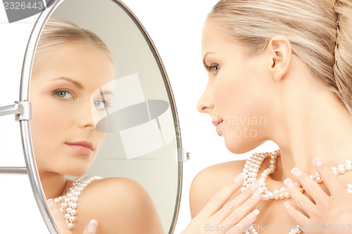 Image of beautiful woman with pearl beads and mirror