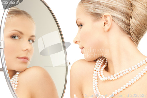 Image of beautiful woman with pearl beads and mirror