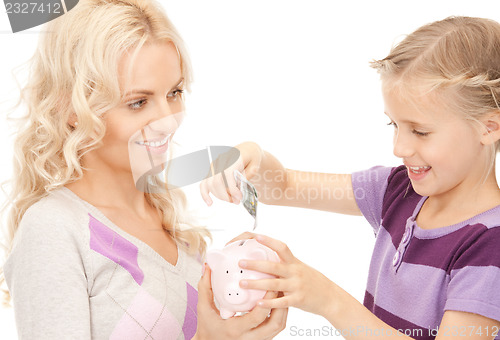 Image of mother and little girl with piggy bank