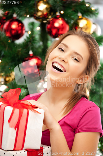 Image of happy woman with gift box and christmas tree