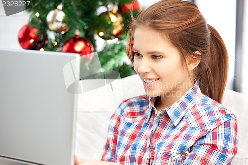 Image of happy woman with laptop and christmas tree