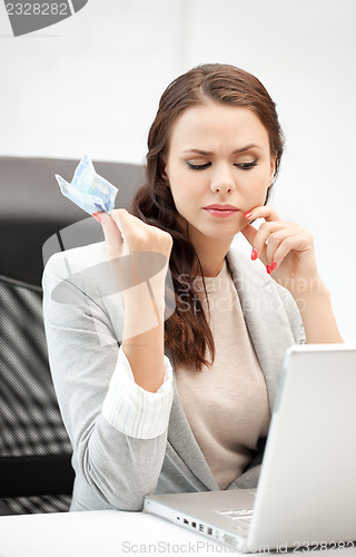 Image of pensive woman with computer and euro cash money