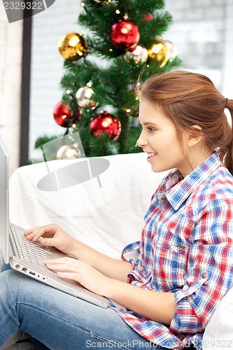 Image of happy woman with laptop and christmas tree