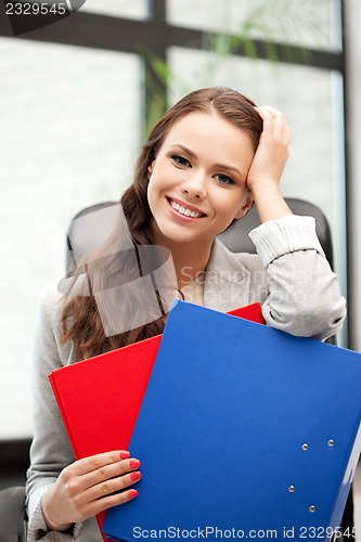 Image of young businesswoman with folders sitting in chair