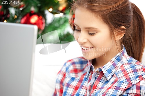 Image of happy woman with laptop and christmas tree