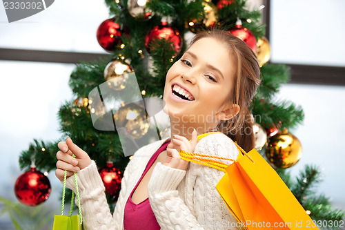 Image of happy woman with shopping bags and christmas tree