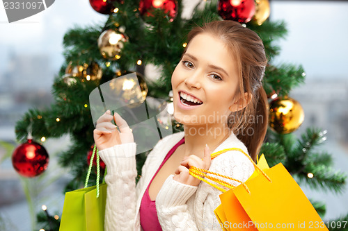 Image of happy woman with shopping bags and christmas tree