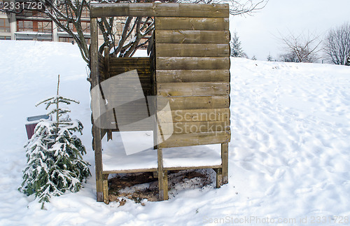 Image of beach changing booth full of snow and small tree  