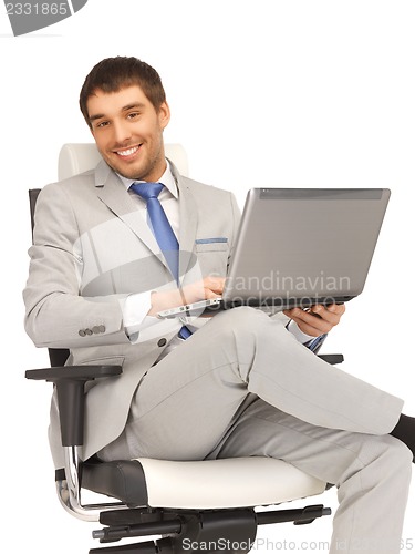 Image of young businessman sitting in chair with laptop