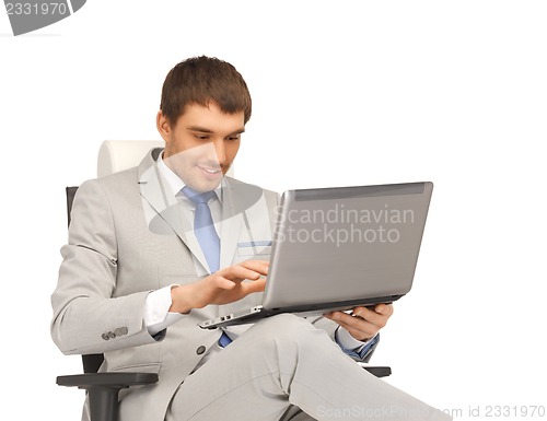 Image of young businessman sitting in chair with laptop