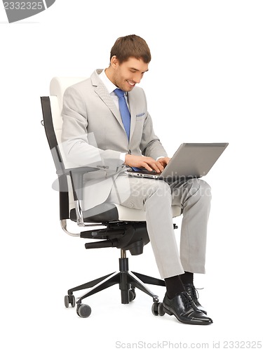 Image of young businessman sitting in chair with laptop