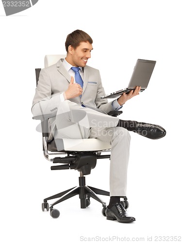 Image of young businessman sitting in chair with laptop