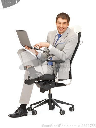 Image of young businessman sitting in chair with laptop