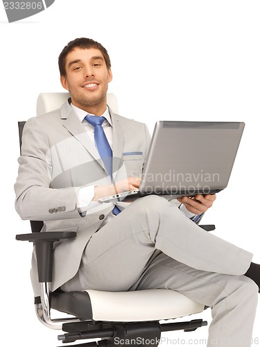 Image of young businessman sitting in chair with laptop