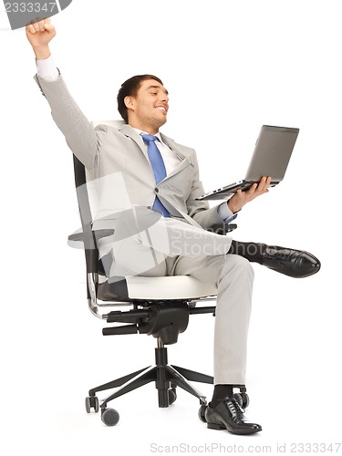 Image of young businessman sitting in chair with laptop