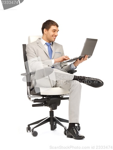 Image of young businessman sitting in chair with laptop