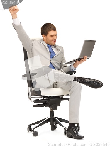 Image of young businessman sitting in chair with laptop