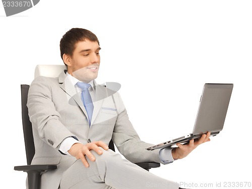 Image of young businessman sitting in chair with laptop