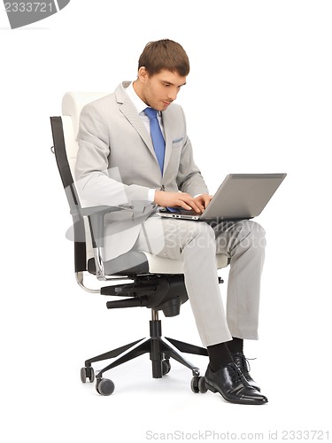 Image of young businessman sitting in chair with laptop