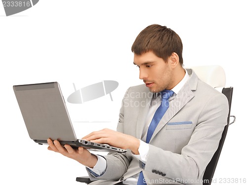 Image of young businessman sitting in chair with laptop