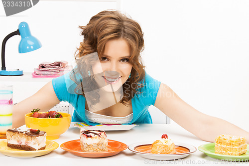 Image of lovely housewife at the kitchen with sweets
